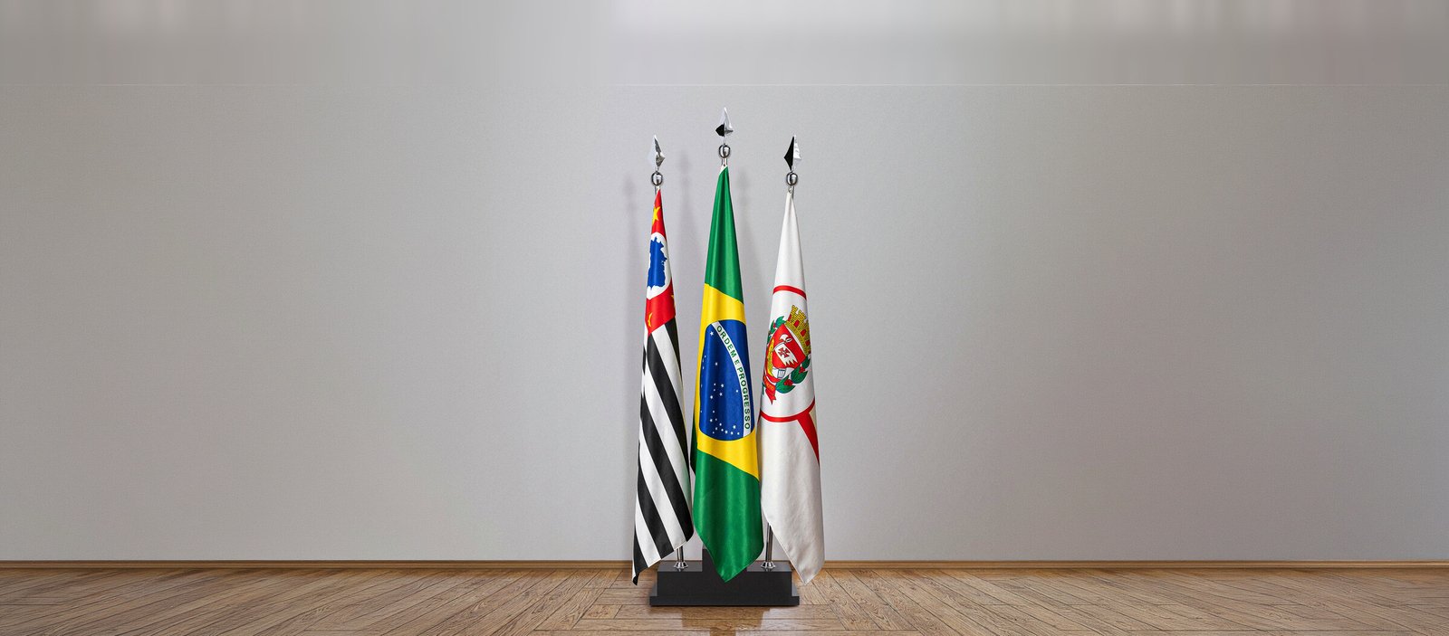 Três bandeiras hasteadas em base preta, ambiente institucional amplo com piso de madeira